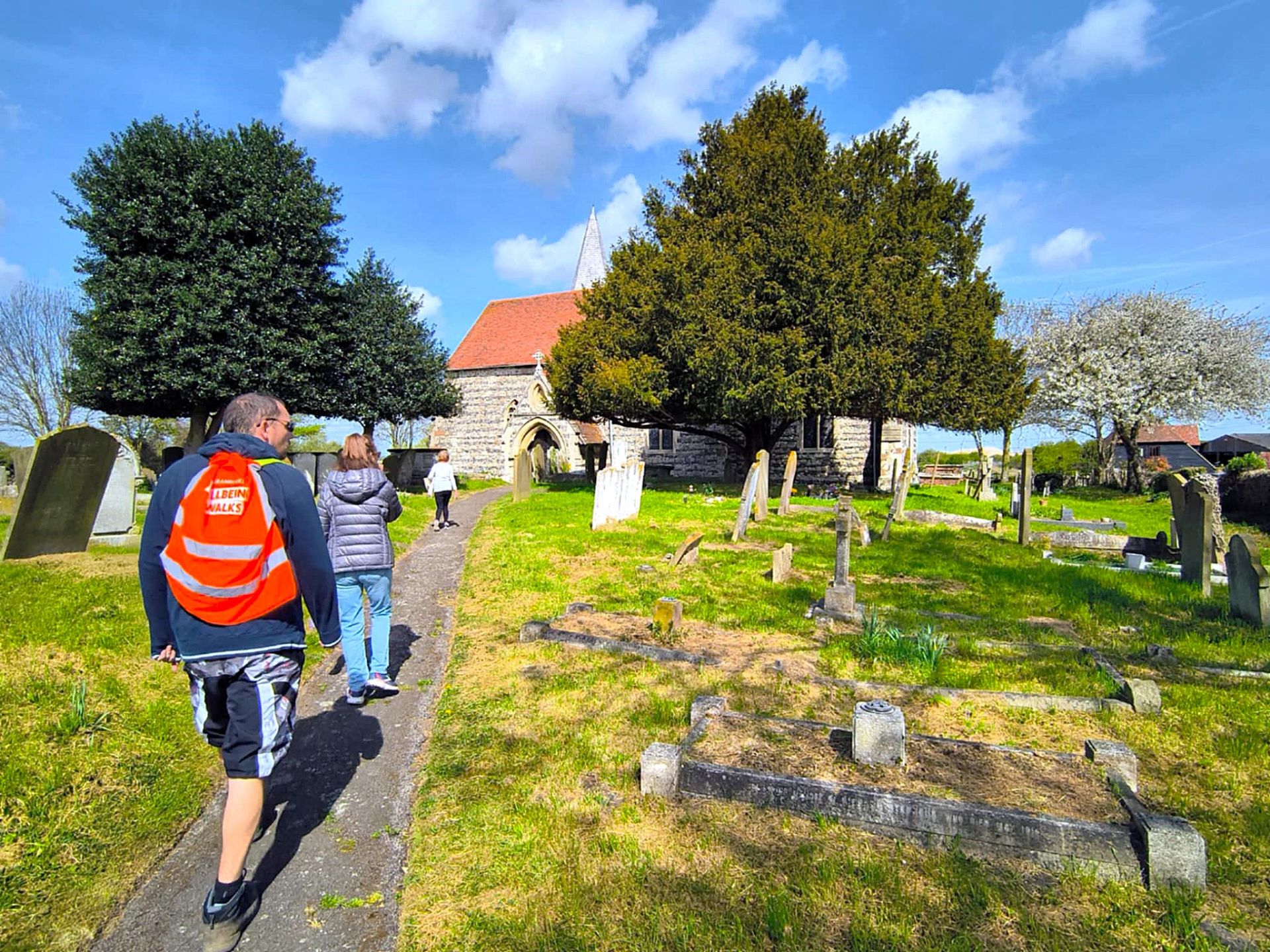 Walking group walk through a graveyard towards a church